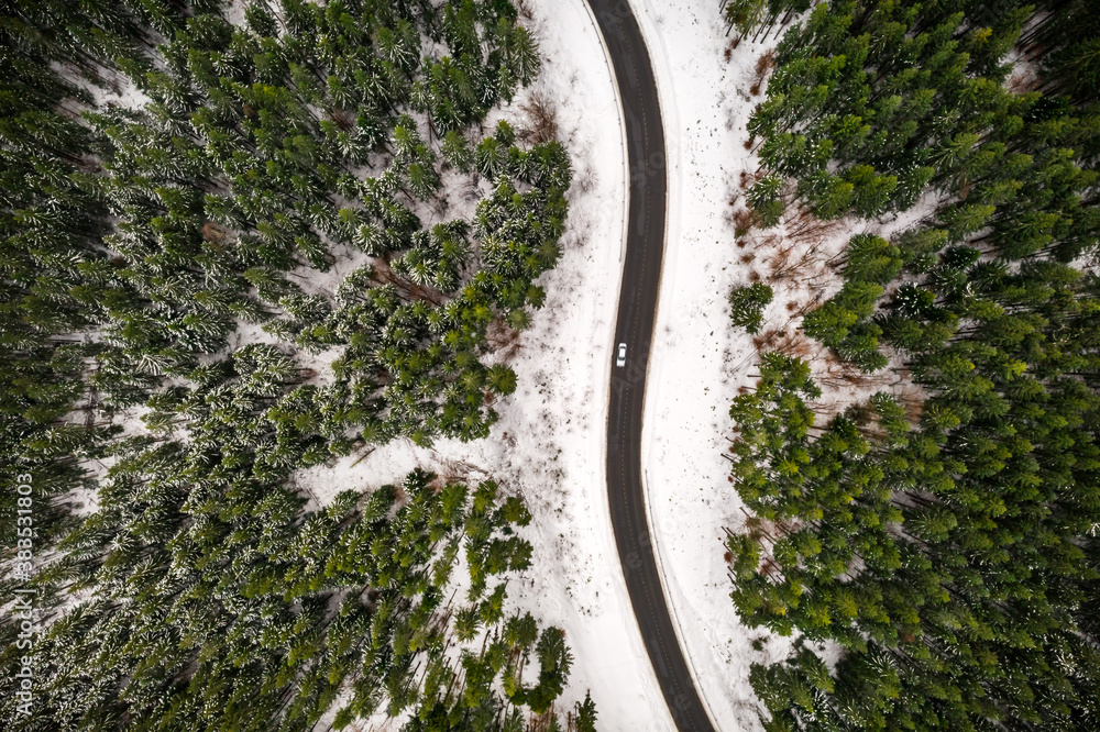 Flight over the winter mountains with road serpentine and snowy forest. Top down view. Landscape pho