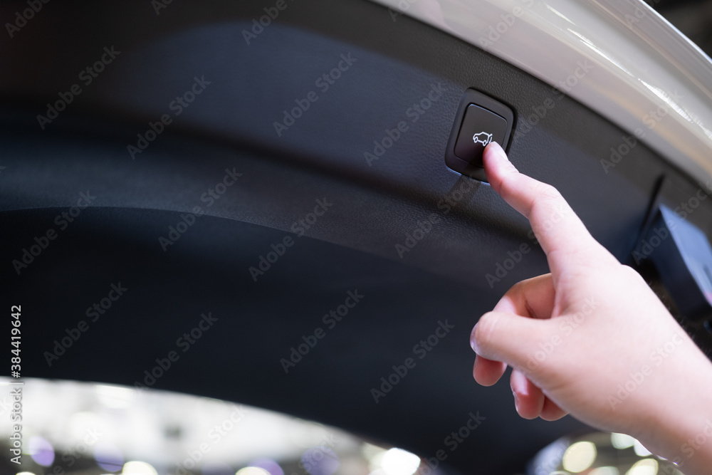 New function of the car, close up hand pushing car trunk to unlock in modern hatchback car