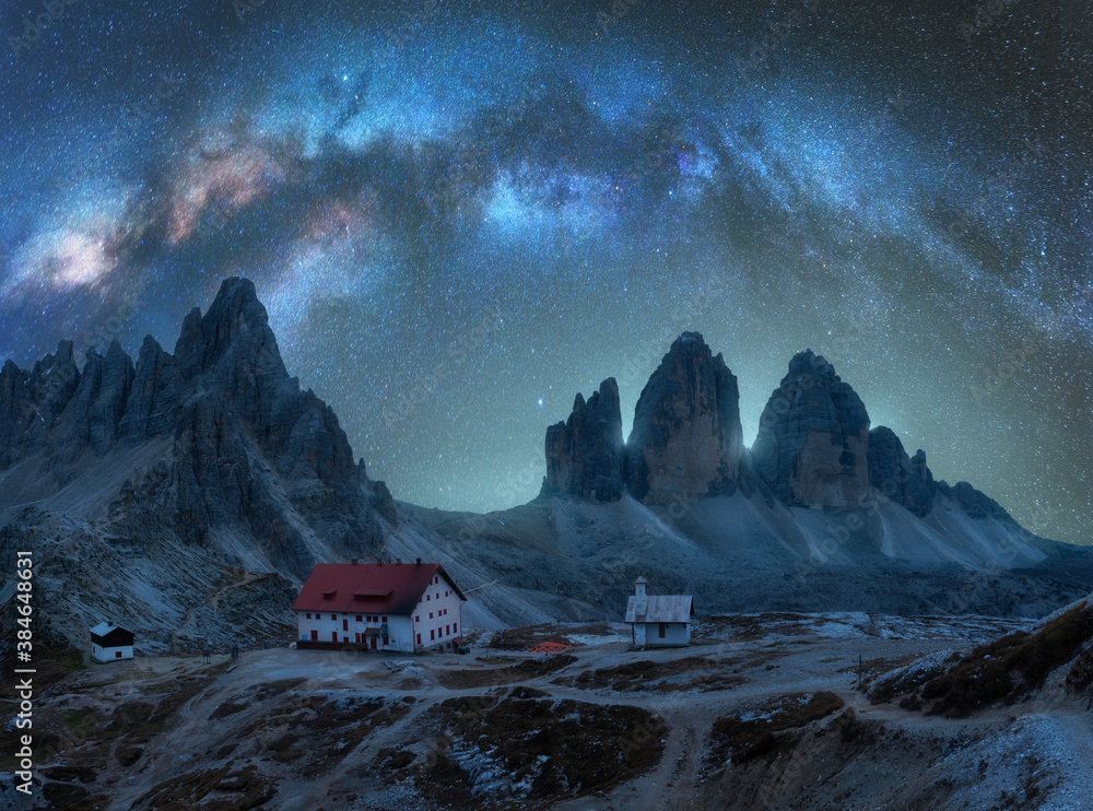 Milky Way arch over mountains at starry night in summer. Landscape with alpine mountains, building, 