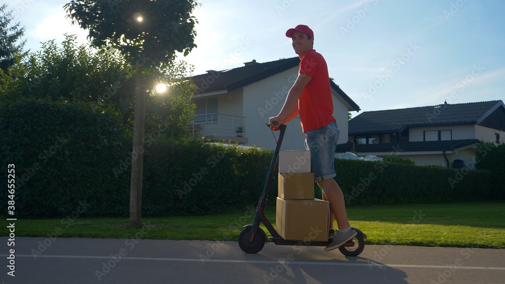 LENS FLARE: Young courier delivers packages on his e-scooter on a sunny day.