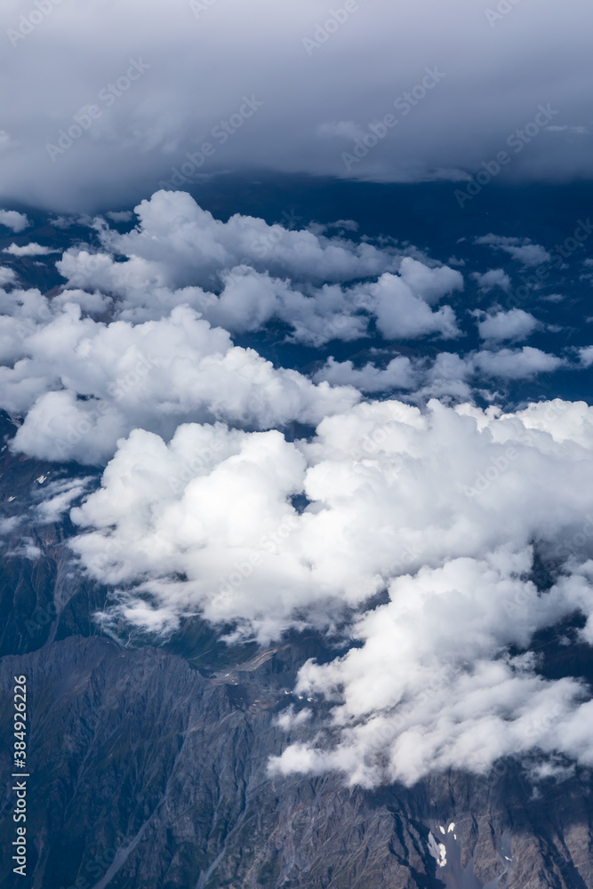 在阳光明媚的日子里，俯瞰云层和山峰。从飞机上俯瞰山景。