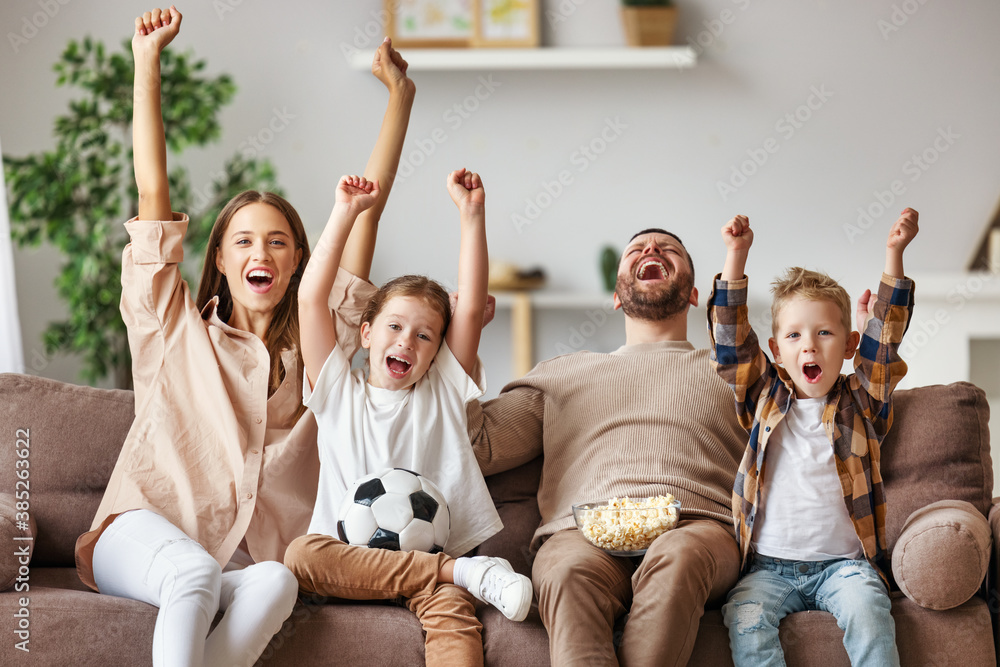 球迷家庭在家观看足球比赛并在电视上庆祝进球。