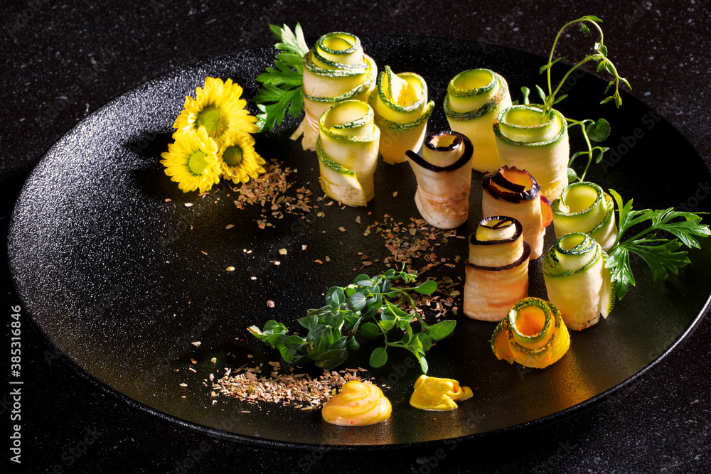 AJVAR ZUCCHINI ROLLS FROM THE GRILL served on black plate on dark background.Menu and design concept