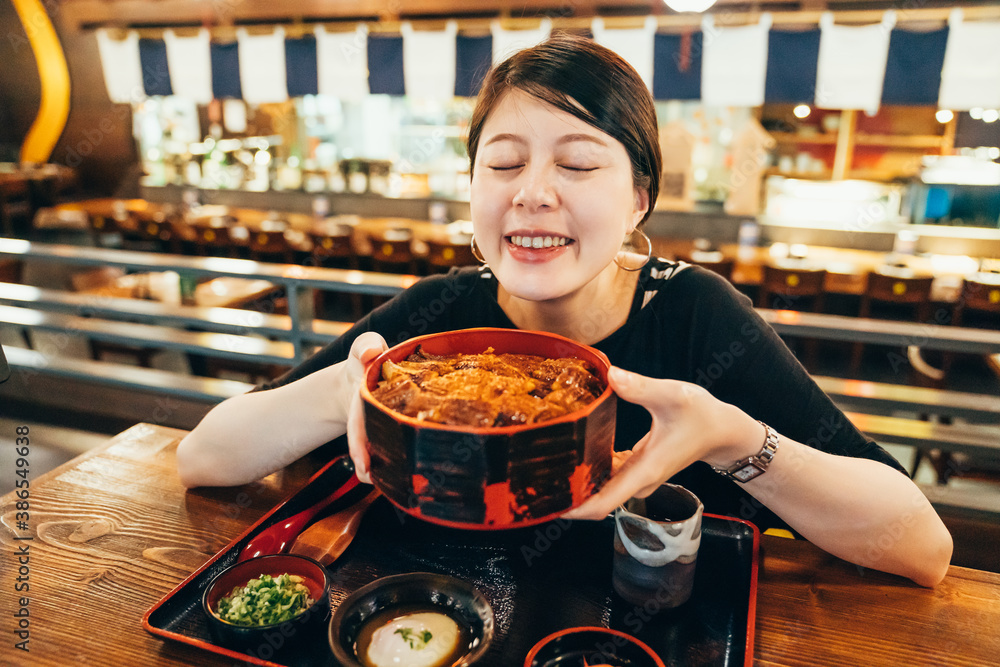 cute asian korean girl smile to camera and hands holding broiled eel served in bowl of rice. beautif