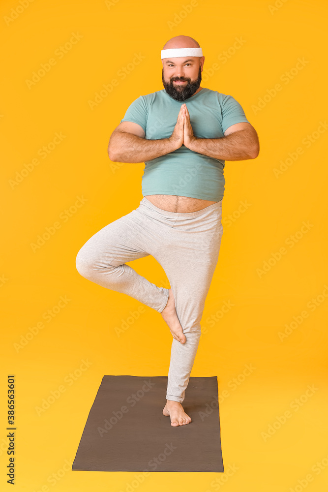 超重男子在彩色背景下练习瑜伽。减肥概念