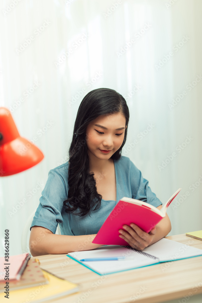 Focused school girl studying with books preparing for test exam writing essay doing homework at home