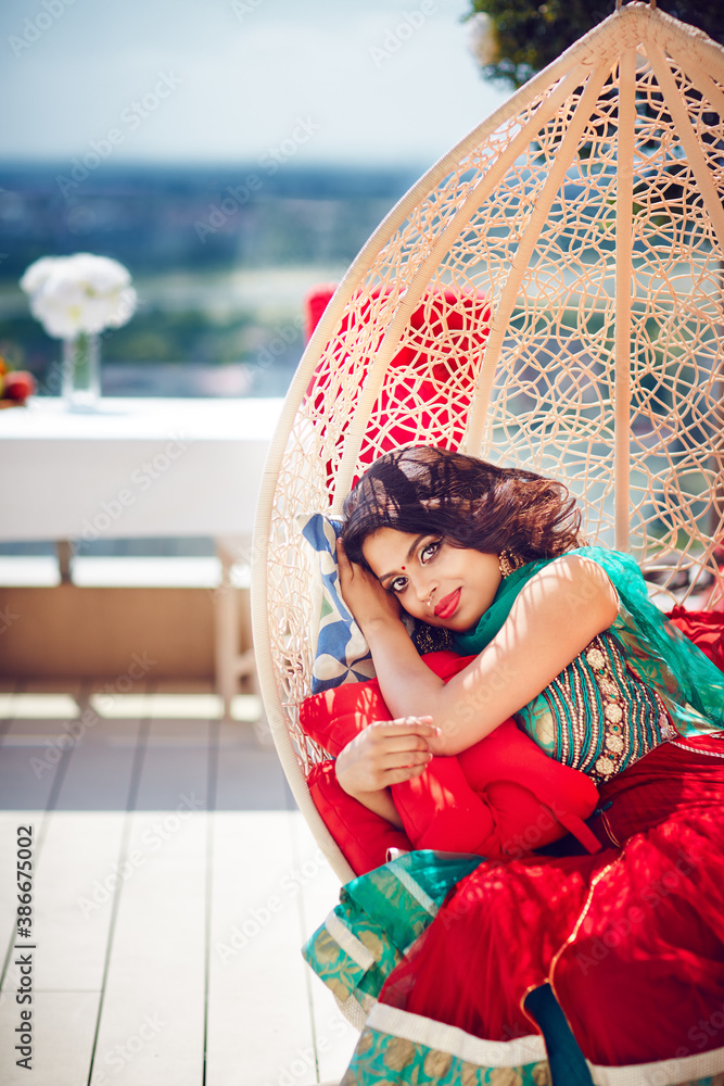 beautiful indian woman relaxing in hanging swing at the patio