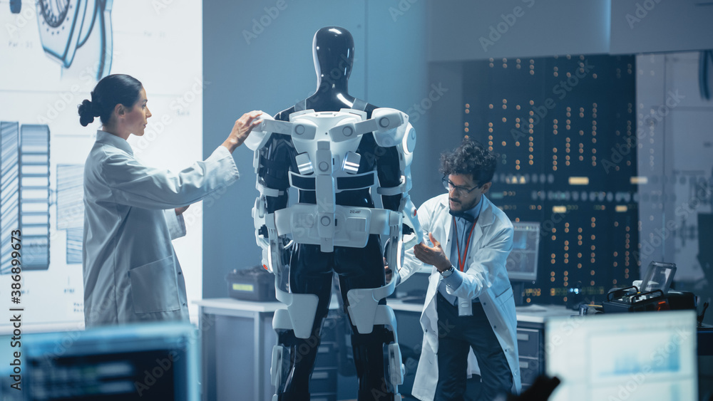Chief Analyst Uses Computer, Female Engineer and Top Male Scientist Work on a Bionics Exoskeleton Pr
