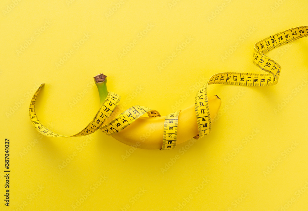 黄色背景上裹着卷尺的香蕉