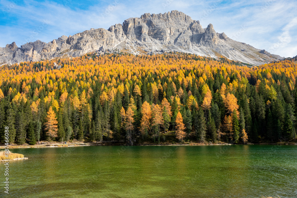 Picturesque view of a mountain towering over a fall colored forest and calm lake