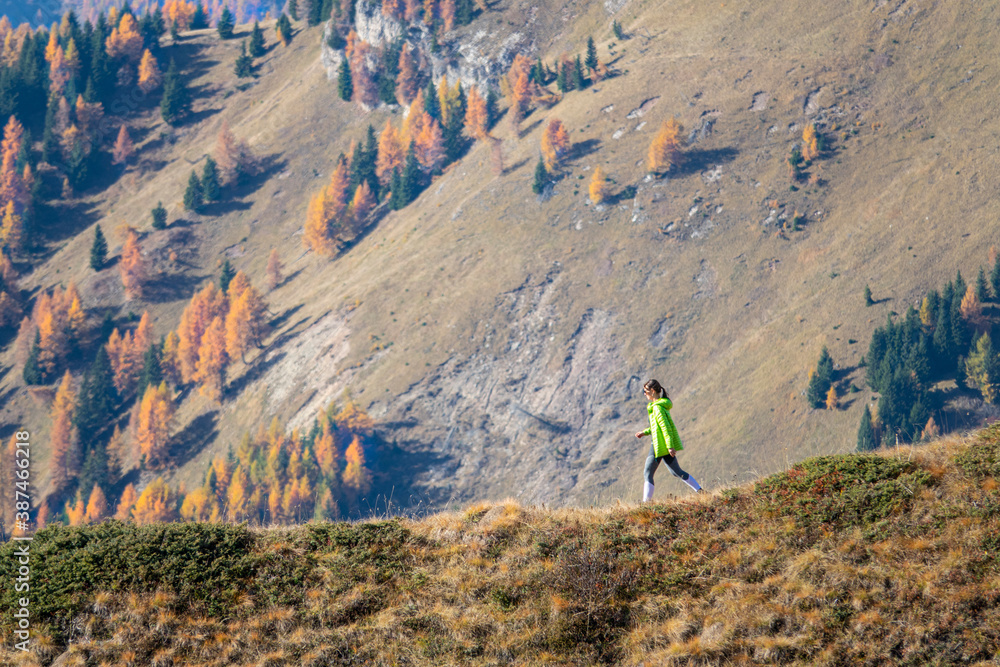 COPY SPACE: Fit young woman hikes down a scenic mountain trail near Passo Giau.