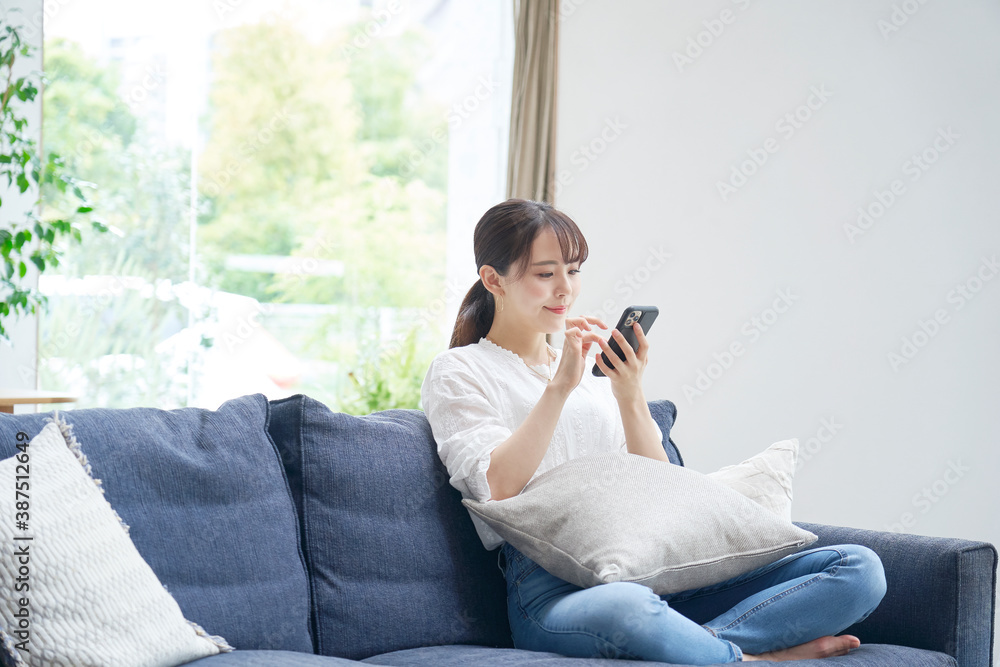 ソファーでスマートフォンを使う女性