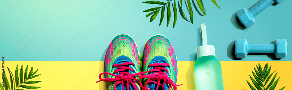 Fitness shoes and dumbbells with tropical plants - flat lay
