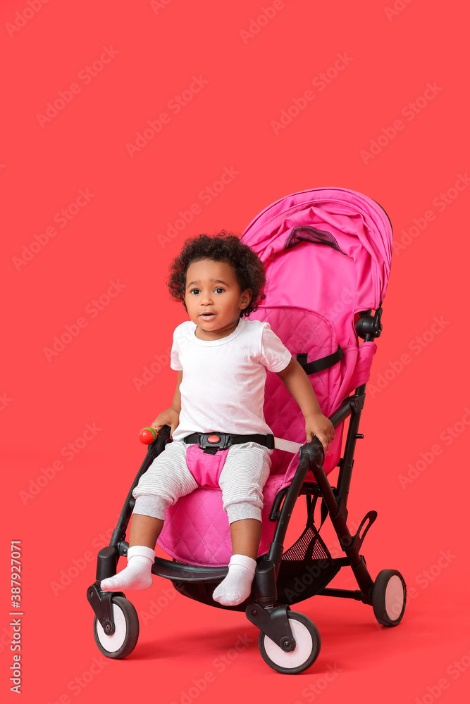 彩色背景婴儿车里的可爱非裔美国婴儿