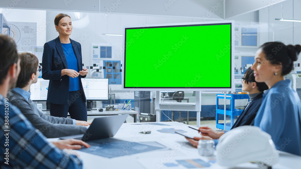 Modern Industrial Factory Meeting: Confident Female Engineer Uses Interactive Green Mock-up Screen W