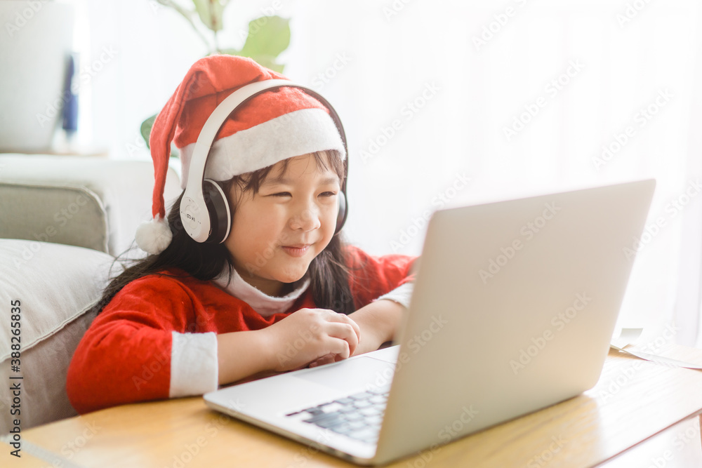亚洲女孩带着圣诞帽参加圣诞派对。快乐女孩在笔记本电脑上聊天视频客串。Tec