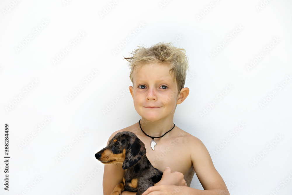 Funny portrait of little child embracing dachshund puppy after outdoor playing. White background. Po
