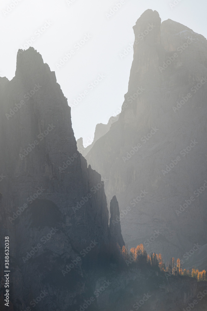VERTICAL: Golden sunbeams shine on a rocky gorge in the picturesque Dolomites.