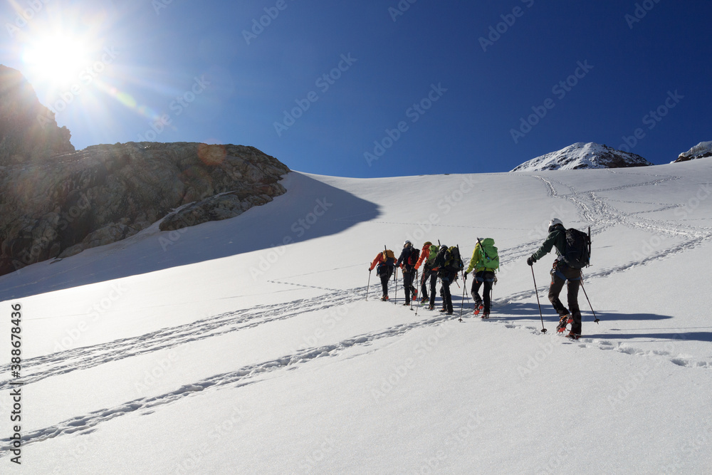 Rope team mountaineering with crampons on glacier Sexegertenferner towards Sexegertenspitze and moun