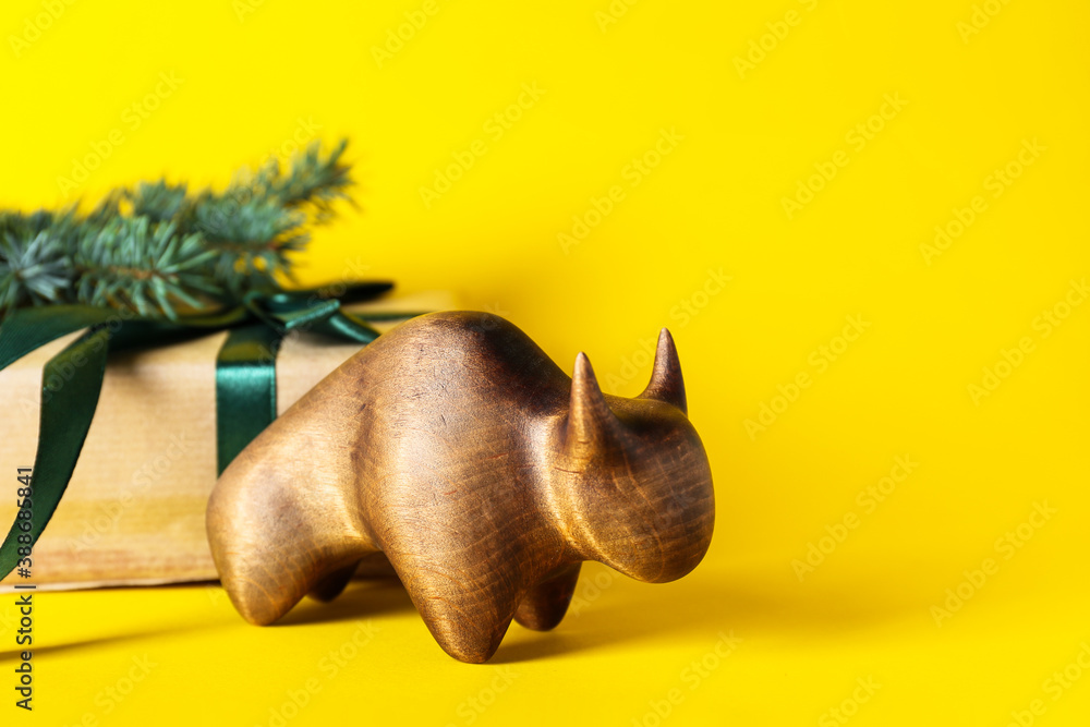 Figurine of bull and New Year gift on color background