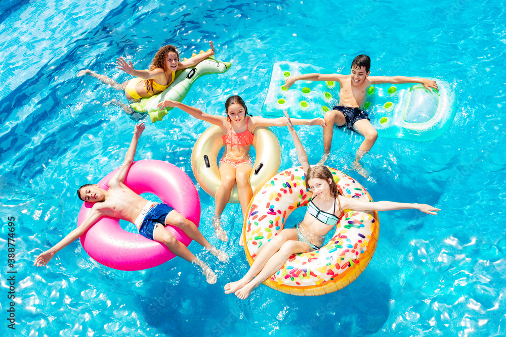 Many happy children friends swim on inflatable ring toys view from above