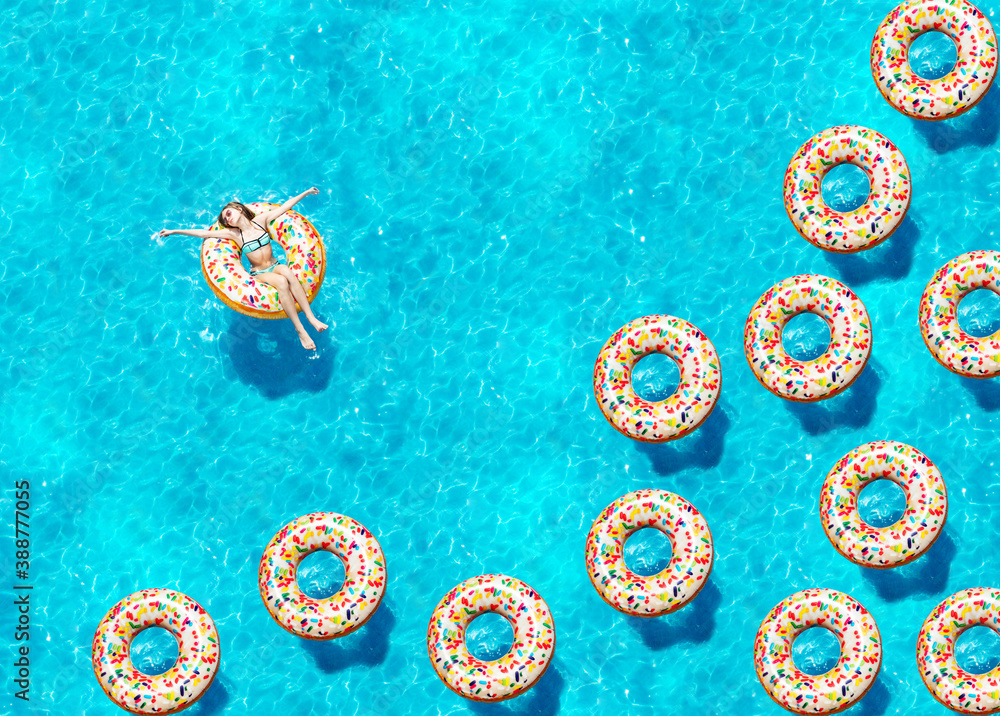 游泳池俯视图中，一个女孩在充气糖果甜甜圈浮标上游泳的肖像