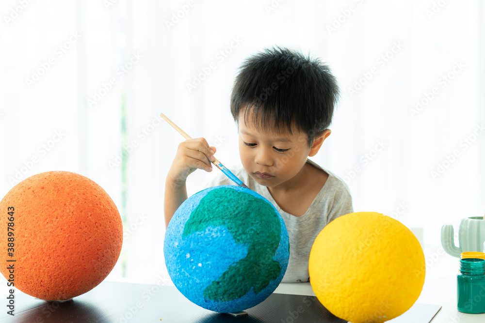 Asian preschool student boy painting the moon learning about the solar system at home, Homeschooling