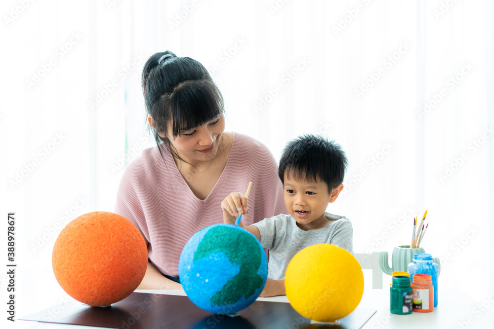 Asian preschool student boy with mother painting the moon learning about the solar system at home, H