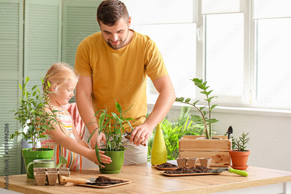 Young father with daughter setting out plants at home