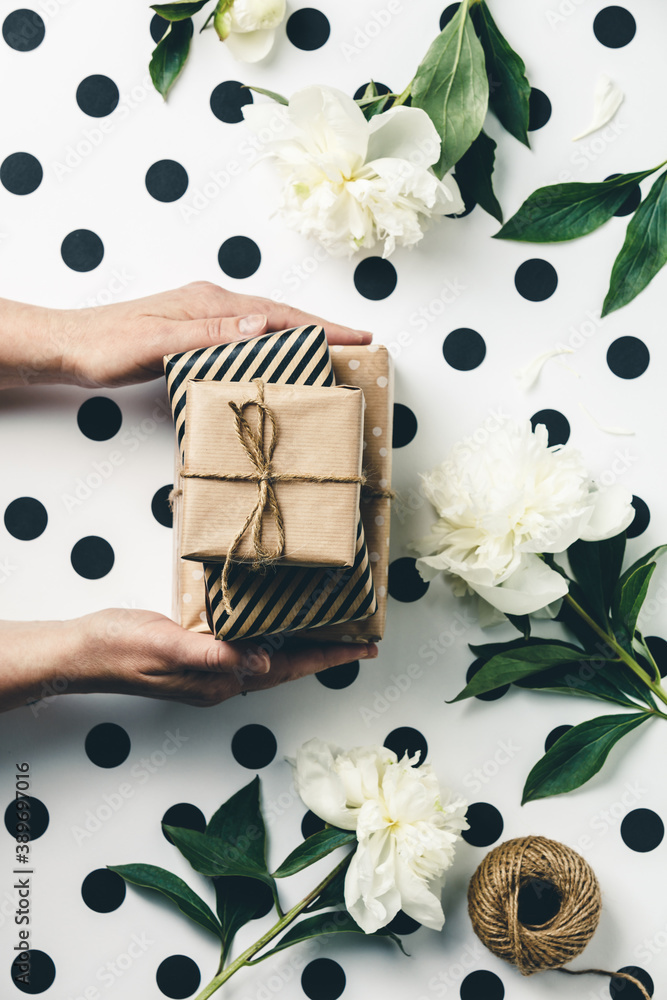 平躺布置，女性手拿礼盒，夹在礼物和鲜花之间，俯视图