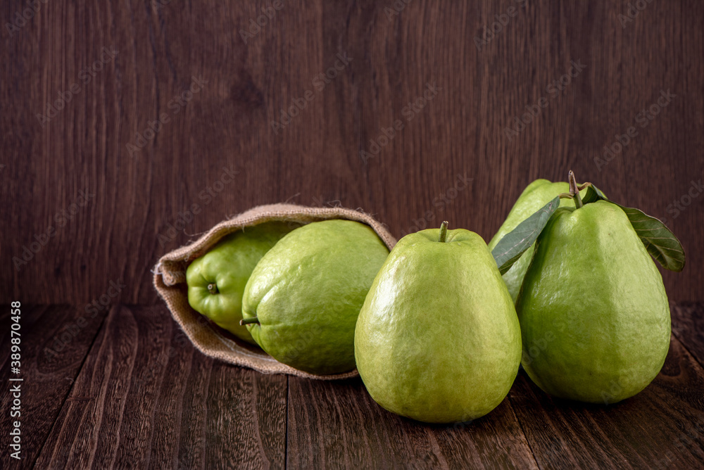 Close up of delicious guava with fresh green leaves on wooden background.