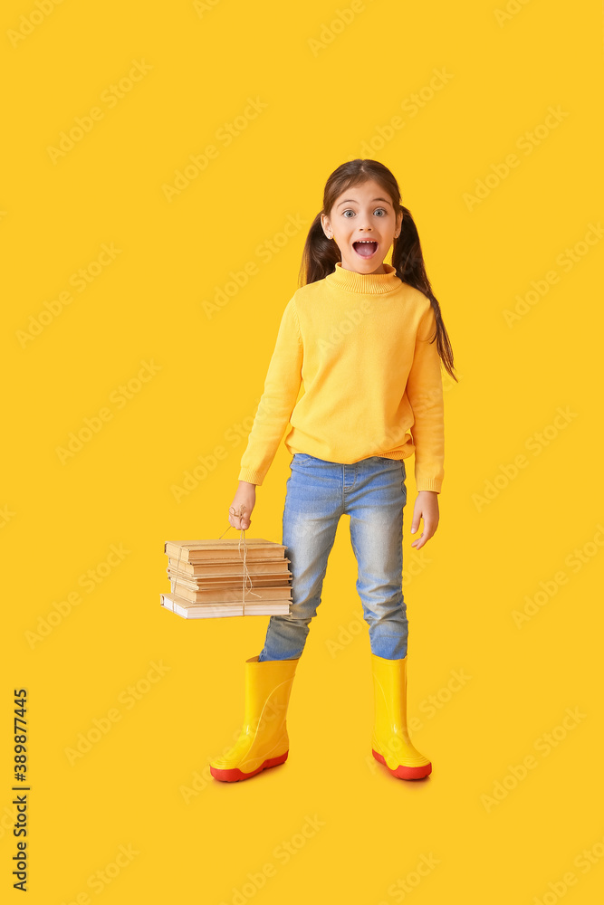 Cute little girl in autumn clothes and with books on color background