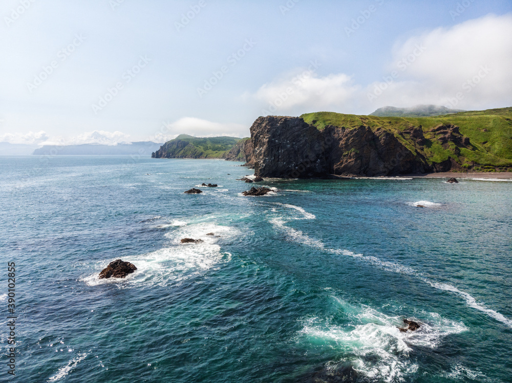 Volcanic landscape with green plains and rocky coast on Kamchatka peninsula