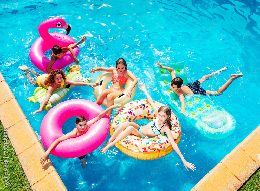 一群快乐的孩子朋友在充气环形玩具上游泳，俯视图