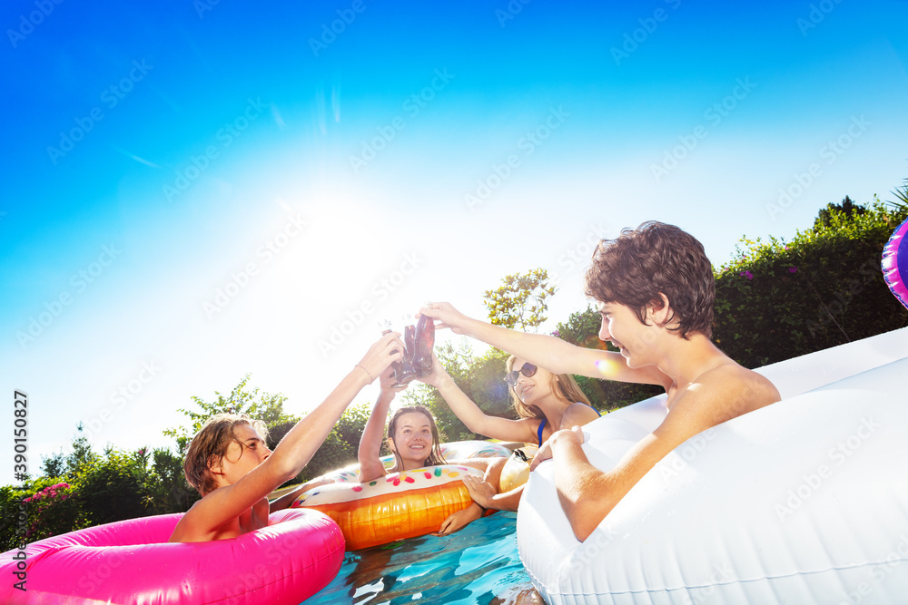 一群孩子在游泳池里欢呼庆祝派对，喝瓶装苏打水