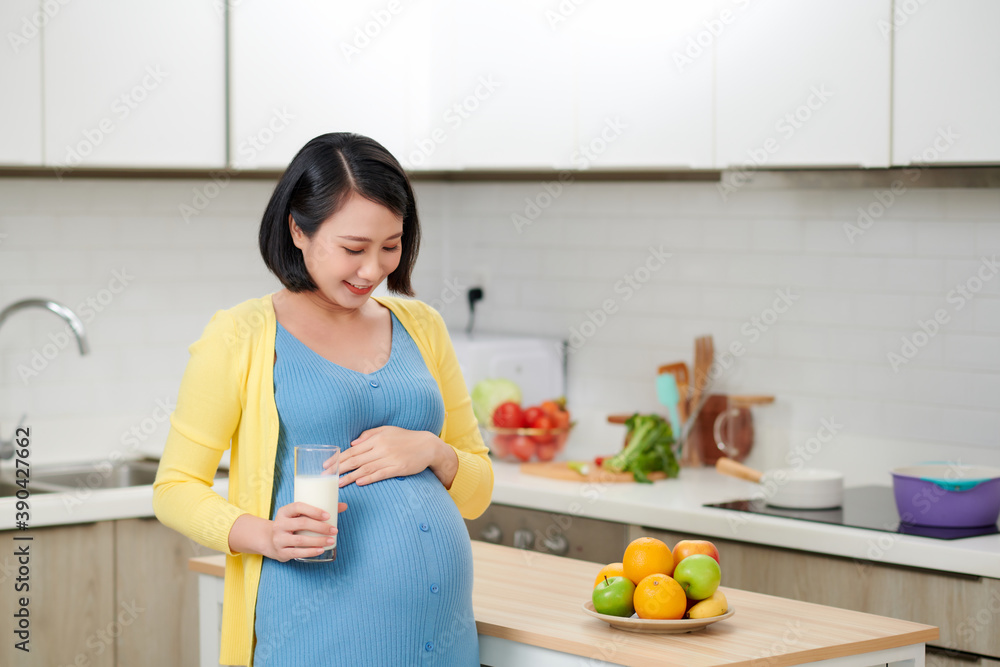 在厨房喝牛奶的快乐孕妇