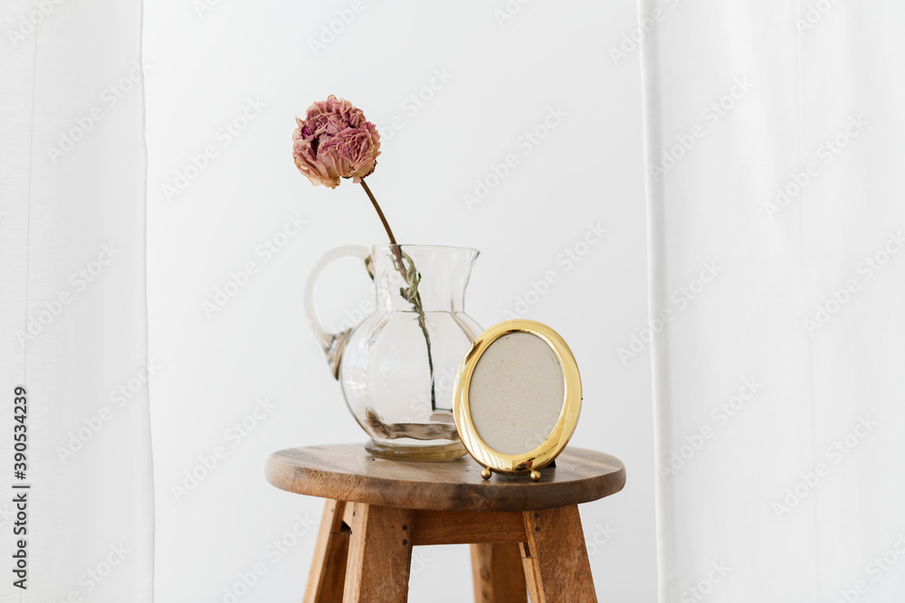 白色房间木制凳子上的玻璃罐中的干牡丹花
