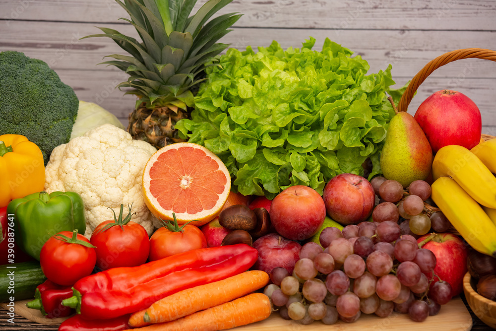 将蔬菜和水果苹果、葡萄、橙子和香蕉与胡萝卜放在木篮子里。