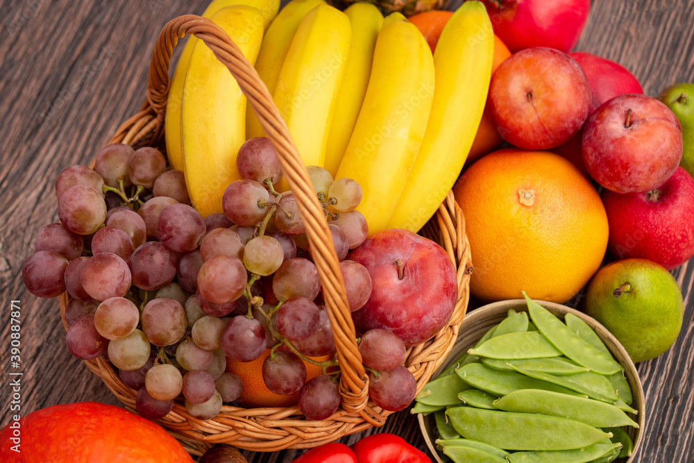 将蔬菜和水果与胡萝卜一起放在木篮子里，苹果、葡萄、橙子和香蕉，