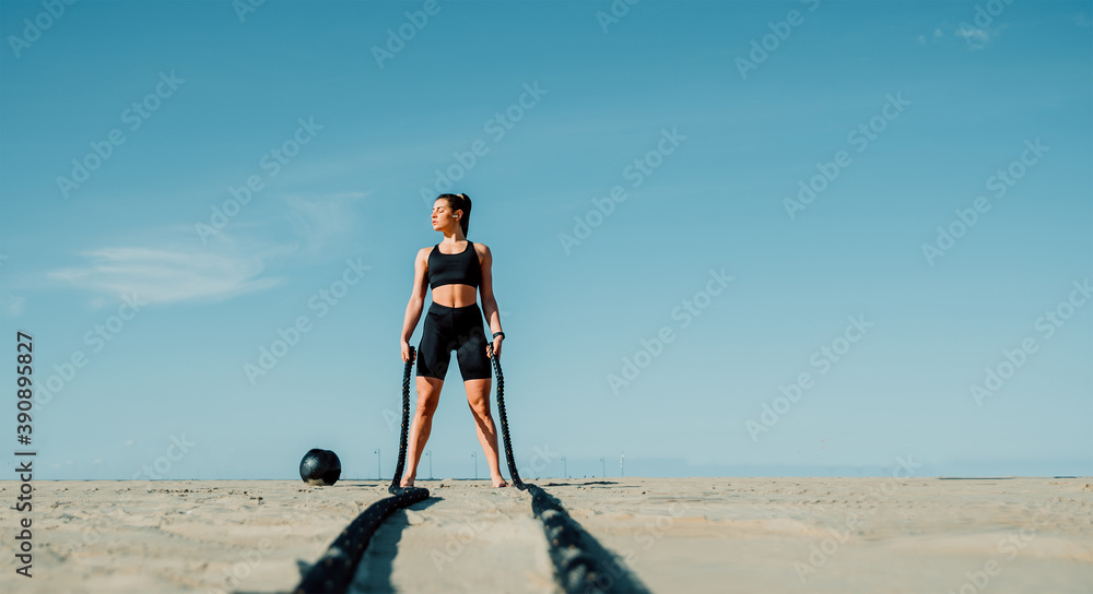 身材健美的女运动员在海滩的功能训练健身房锻炼——绳索训练