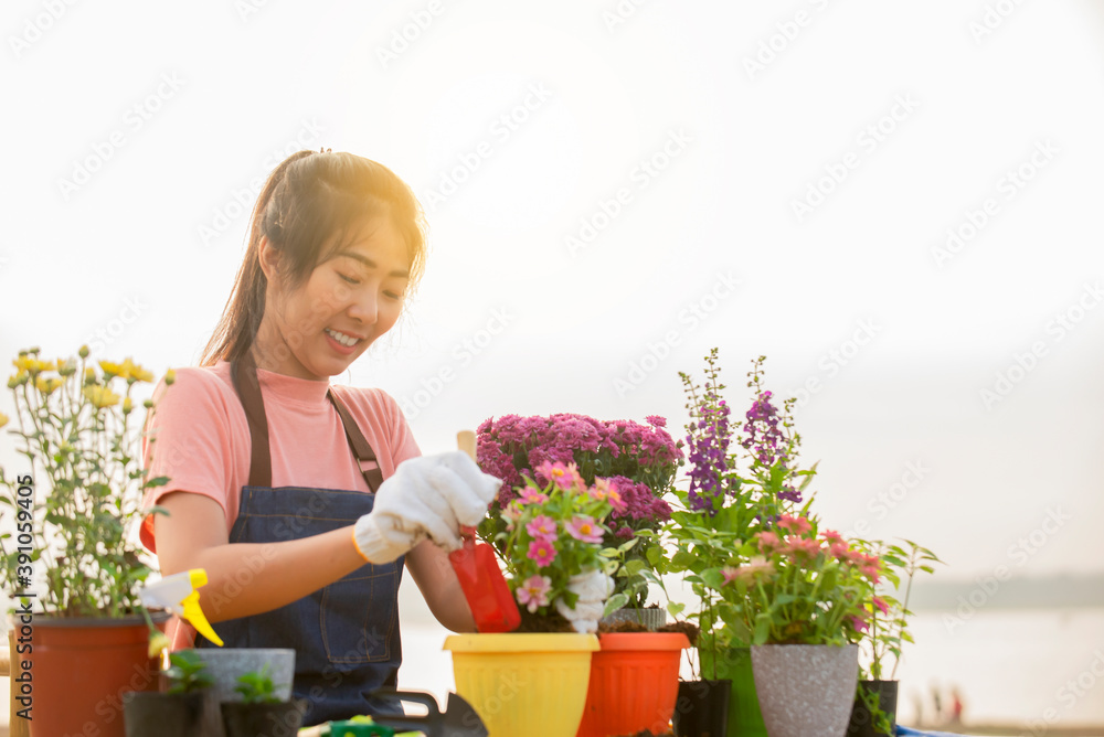 戴着手套的亚洲年轻女子在户外花园里种花