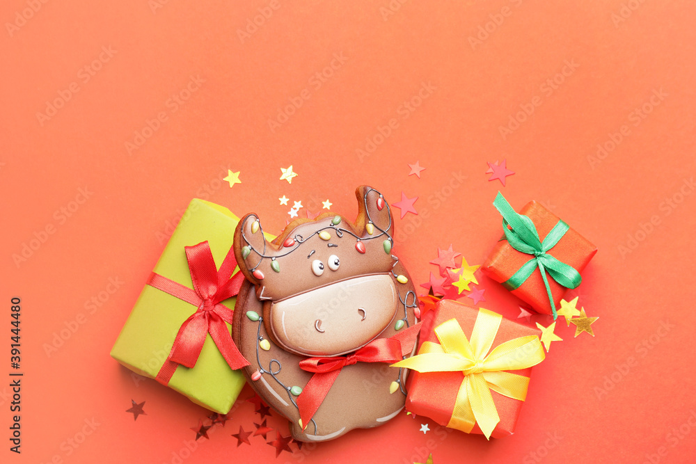 公牛形状的美味饼干和彩色背景的圣诞礼物