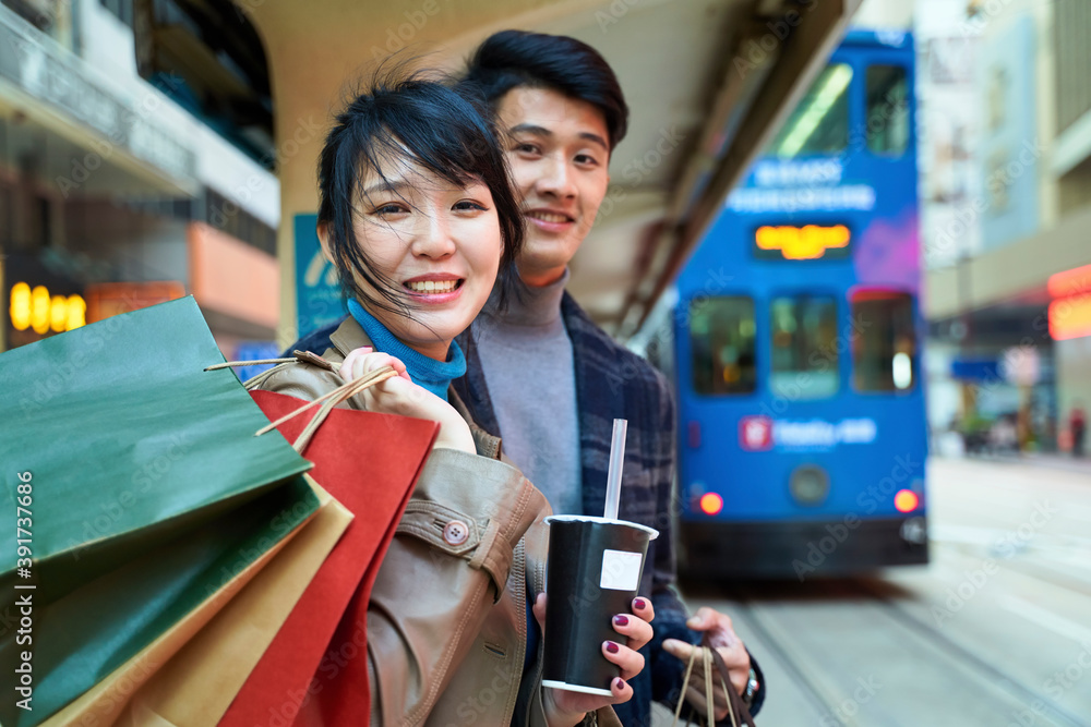 幸福的亚洲年轻夫妇在现代城市等公交车