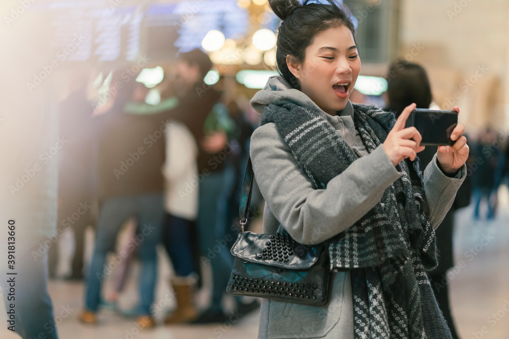 年轻的亚洲女性旅行者观光并享受先进时刻，手持智能手机拍照