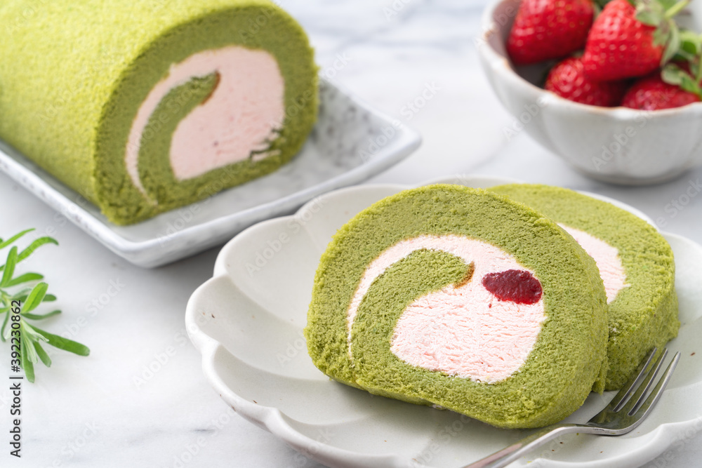 Delicious Matcha Swiss Roll Cake slices with strawberry cream on white background.