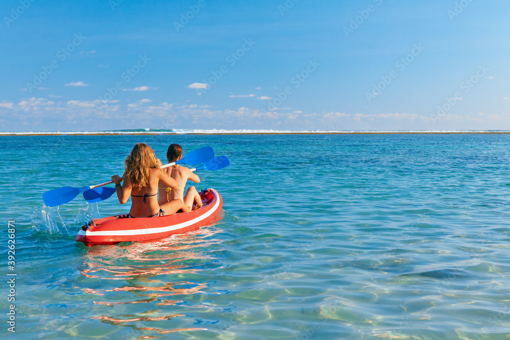年轻女性在划船时玩得很开心。女孩们在泻湖边的皮划艇上划水。旅行生活方式，娱乐