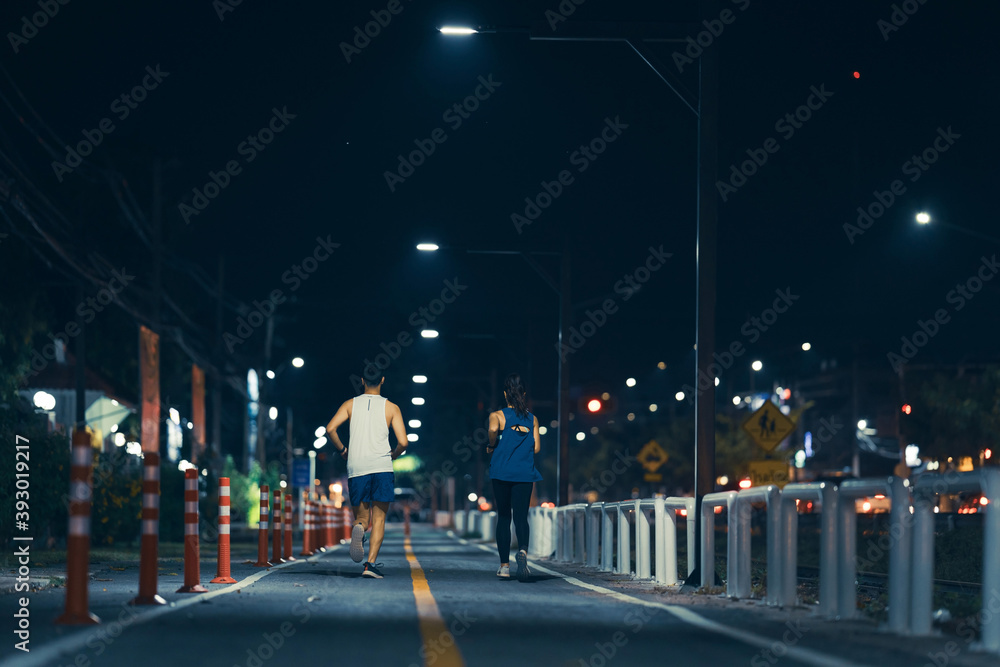 亚洲情侣夜晚在城市街道慢跑