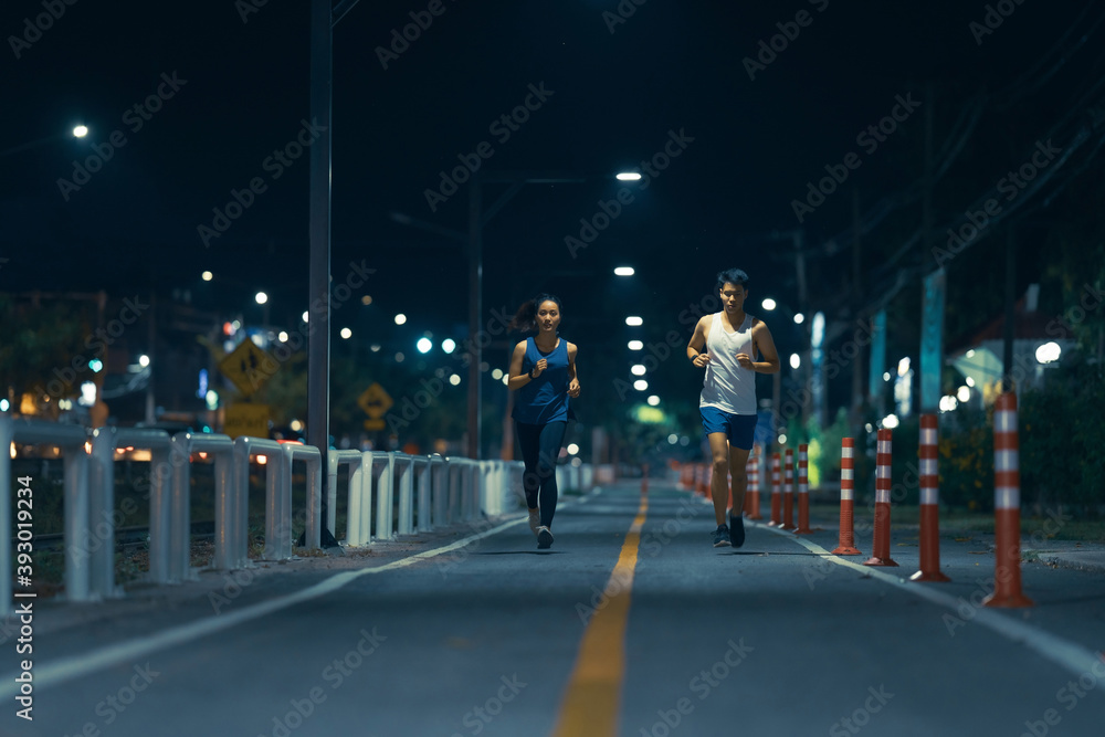 亚洲情侣晚上在城市街道上慢跑