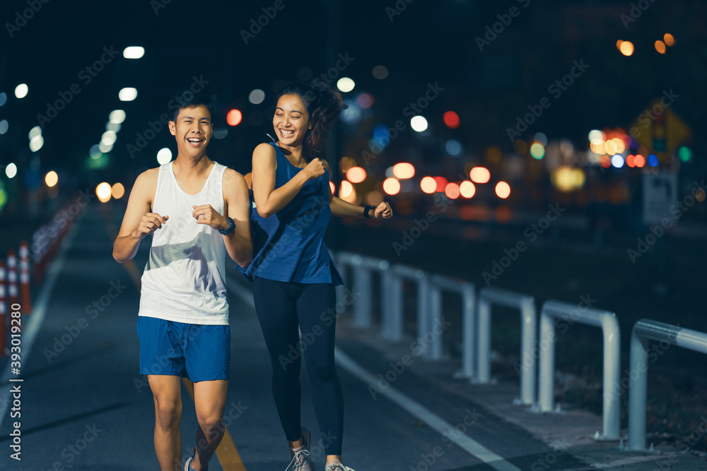 一对亚洲夫妇晚上在城市街道上慢跑。他们很享受