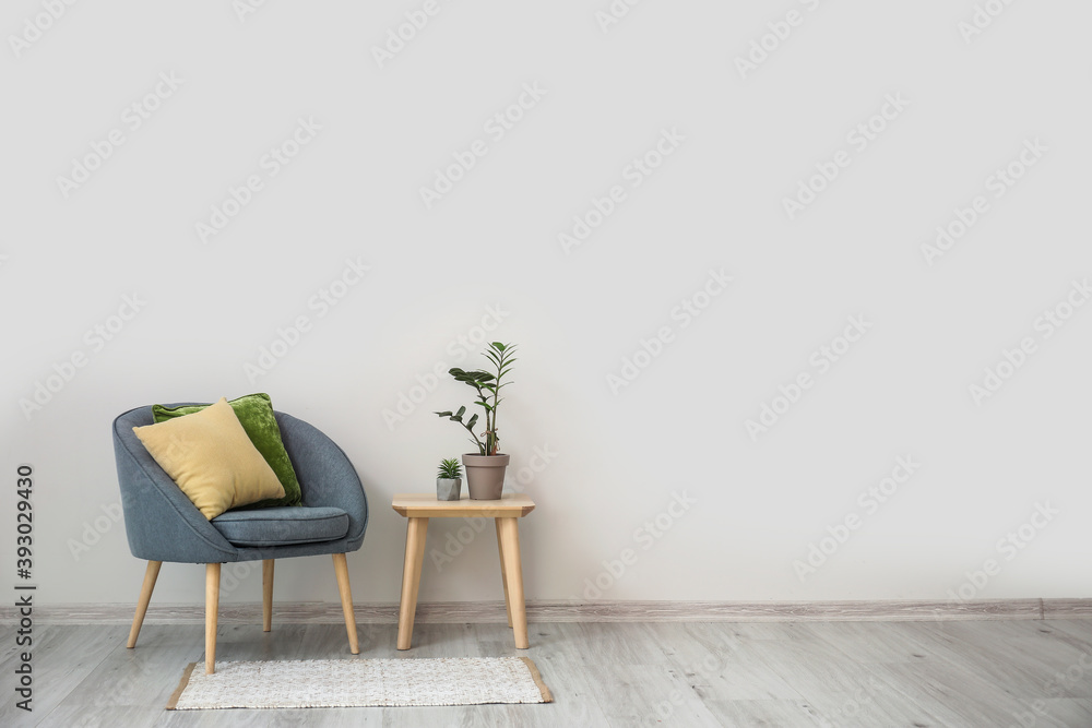 时尚的扶手椅，配有枕头、桌子和室内植物，靠近室内的光墙